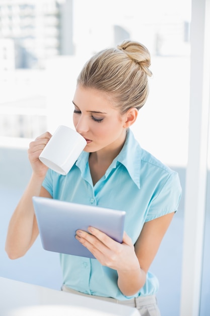 Donna elegante rilassata che utilizza compressa mentre bevendo caffè