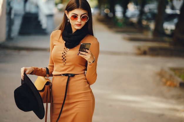 donna elegante usa il suo cellulare mentre cammina per la città in una giornata soleggiata e calda