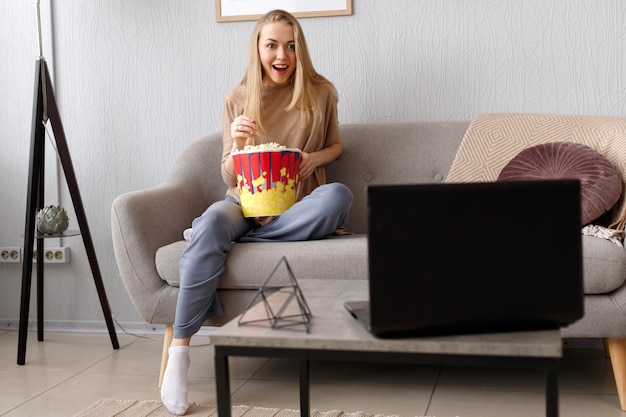 Donna emotiva sul divano con popcorn guardando la TV