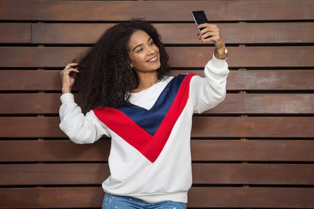 Donna etnica sorridente che prende selfie