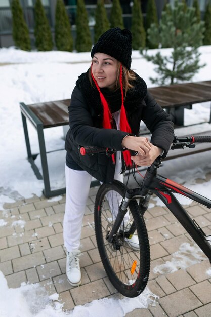 Donna europea in abiti da inverno che va in bicicletta in inverno