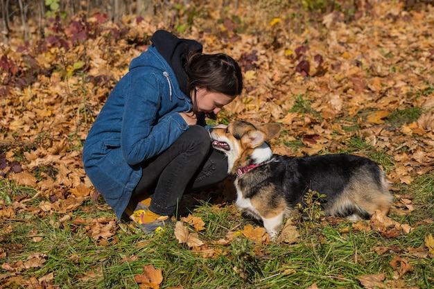Donna europea parlando con il cane pembroke welsh corgi nella foresta di autunno
