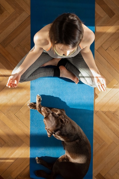 Donna europea sulla stuoia di yoga blu che medita a casa