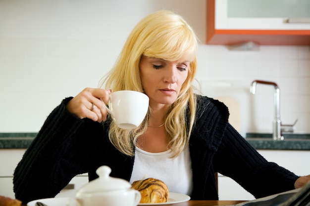 donna facendo colazione e leggendo il giornale