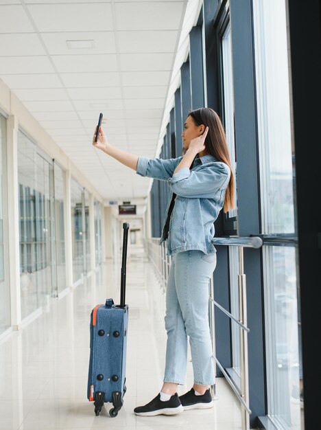 Donna felice che aspetta il volo all'aeroporto