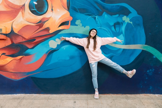 Donna felice che balla davanti al muro di graffiti colorati