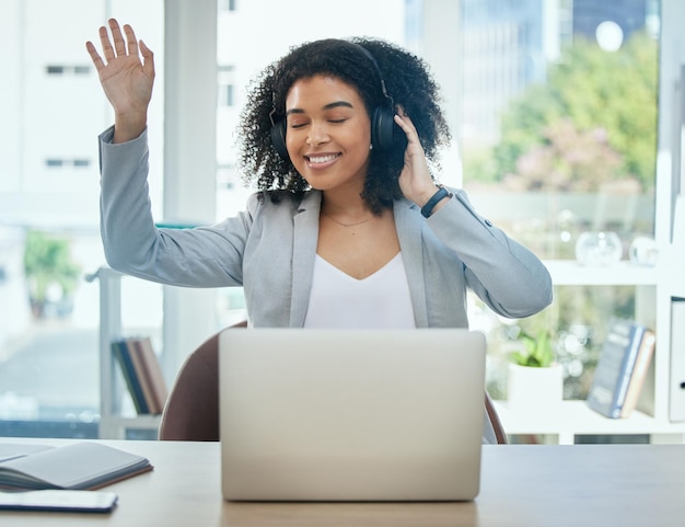 Donna felice che balla e cuffie musicali dal laptop dell'ufficio per energia divertente o motivazione aziendale Sorriso danza e lavoratore che ascolta podcast audio o radio su tecnologia aziendale o app per cuffie