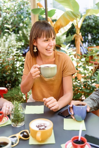 Donna felice che beve caffè con gli amici