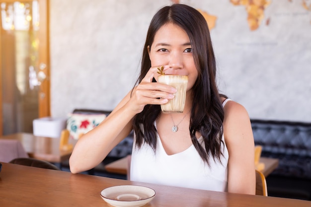 Donna felice che beve caffè nella caffetteria moderna, prenditi una pausa caffè