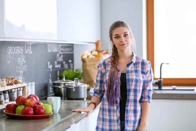 Donna felice che beve il tè in cucina a casa