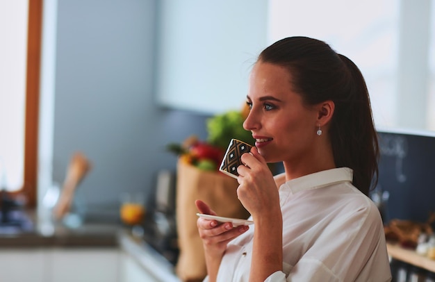 Donna felice che beve il tè in cucina a casa