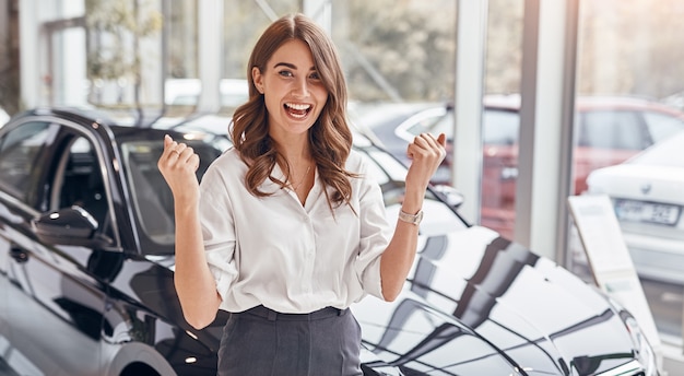 Donna felice che celebra l'acquisto di un'auto nuova