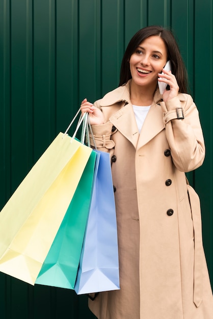 Donna felice che comunica sul telefono all'aperto mentre si tengono le borse della spesa