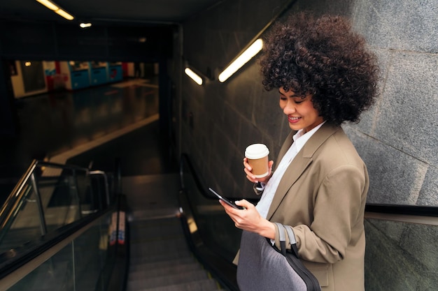 Donna felice che controlla il telefono sulla scala mobile