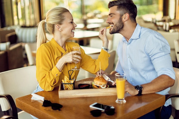 Donna felice che dà da mangiare al suo ragazzo mentre pranza in un ristorante