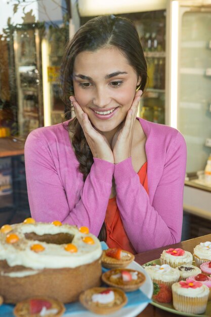 Donna felice che esamina l'esposizione del dessert