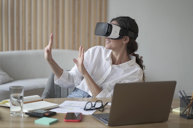 Donna felice che esplora il mondo aumentato al lavoro toccando oggetti virtuali 3d con le mani