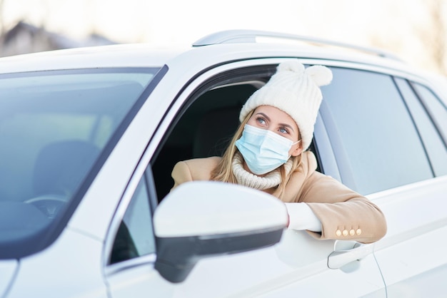 Donna felice che guida l'auto in inverno nevoso che indossa la maschera. Foto di alta qualità