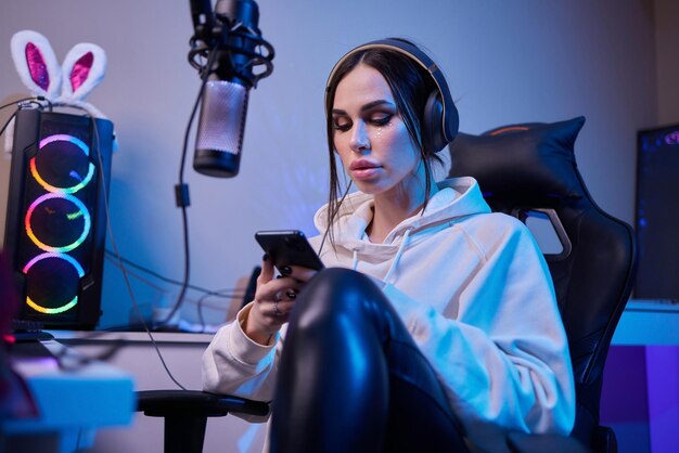 Donna felice che indossa le cuffie e che gioca al computer Gamer femmina con gli occhiali seduto e guardando il monitor del computer