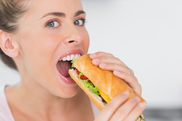 Donna felice che mangia panino e che guarda l&#39;obbiettivo