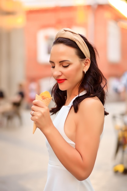 Donna felice che mangia un delizioso cono gelato durante un viaggio di vacanza
