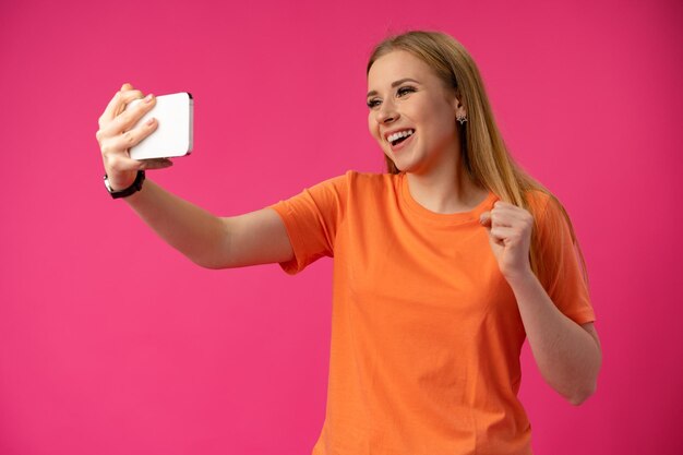 Donna felice che prende selfie contro il colore di sfondo dello studio