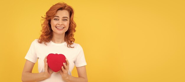 Donna felice che presenta un cuore rosso su sfondo giallo Valentino signora donna ritratto di viso isolato