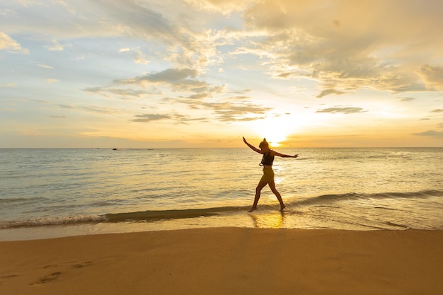Donna felice che salta in mare Tramonto Silhouette di tramonto concetto di vacanza felice