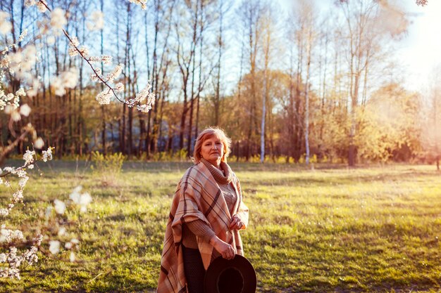 Donna felice che si distende nel giardino di primavera. Donna senior che cammina nel campo.