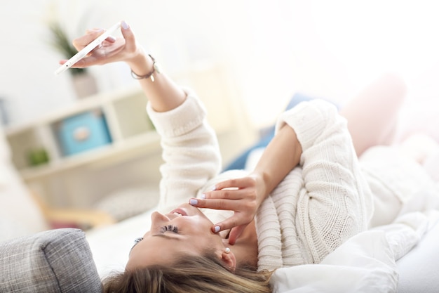 donna felice che si fa un selfie a letto