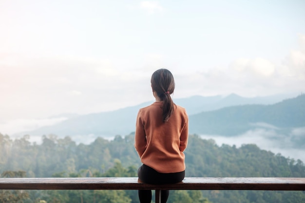 Donna felice che si rilassa e guarda la vista sulle montagne a casa di campagna o in famiglia al mattino. Vacanza, blogger, SoloTravel, viaggio, viaggio e concetto di relax