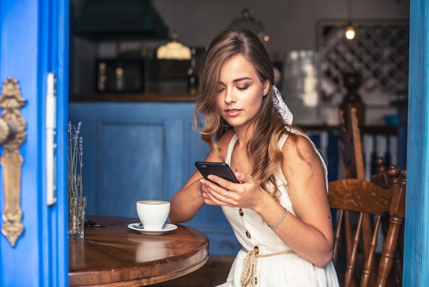 donna felice che si siede nella caffetteria parlando al telefono cellulare.