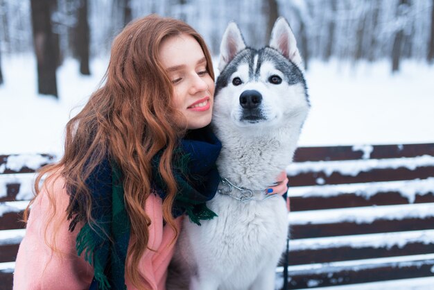 Donna felice che si siede sulla panchina con husky