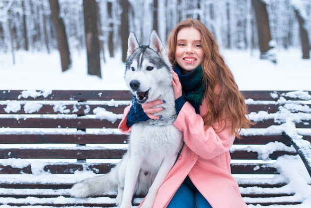 Donna felice che si siede sulla panchina con il husky siberiano