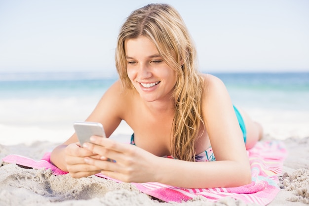 Donna felice che si trova sulla spiaggia e che per mezzo del telefono cellulare