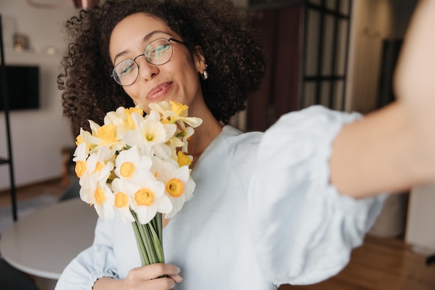 Donna felice che sorride alla macchina fotografica con i fiori