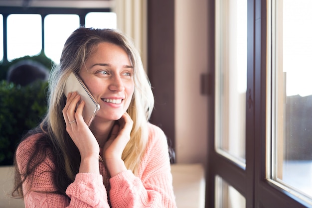 Donna felice che sorride e che parla sul telefono