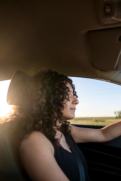 Donna felice che sorride mentre guida un'auto sulla strada