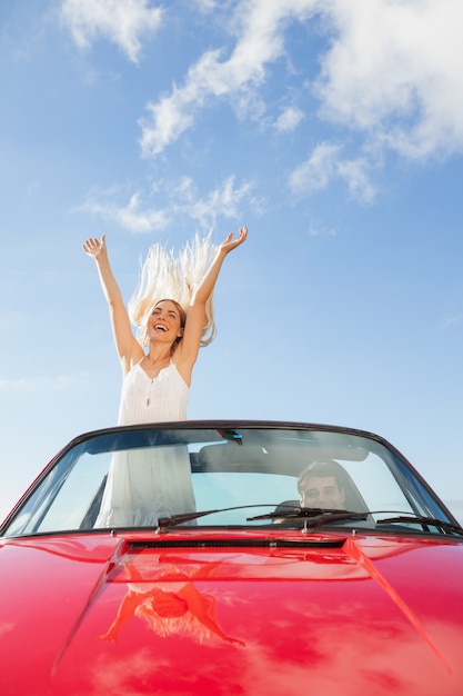 Donna felice che sta in cabriolet mentre il suo ragazzo che guida