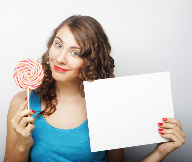 Donna felice che tiene carta in bianco e lecca-lecca. Su sfondo bianco sorridente ritratto femminile.