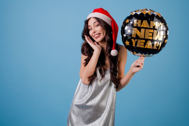 Donna felice che tiene il pallone del buon anno e che porta il cappello di Santa