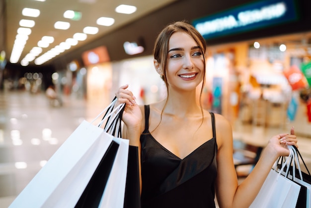 Donna felice che tiene le borse della spesa e sorridente al centro commerciale