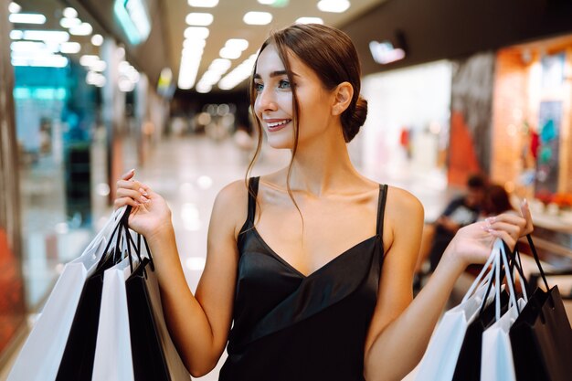 Donna felice che tiene le borse della spesa e sorridente al centro commerciale