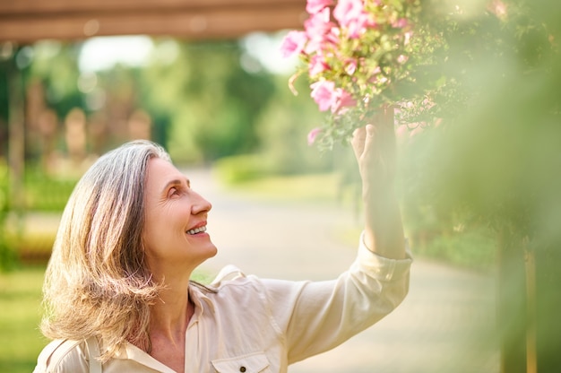 Donna felice che tocca i fiori nel parco