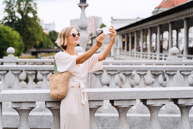 Donna felice che usa lo smartphone sul ponte triplo di Ljubljana, Slovenia, Europa