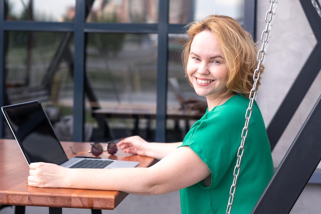 Donna felice che utilizza l'applicazione sul computer portatile digitale in un caffè di strada