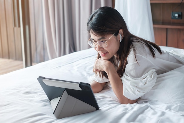 Donna felice che utilizza tablet per i social media giovane donna che guarda film sul pad del computer sul letto a casa rete tecnologica shopping online e commerce stile di vita e concetto di comunicazione digitale