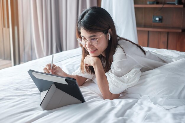 Donna felice che utilizza tablet per i social media giovane donna che guarda film sul pad del computer sul letto a casa rete tecnologica shopping online e commerce stile di vita e concetto di comunicazione digitale