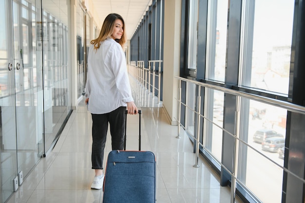 Donna felice che viaggia e cammina in aeroporto