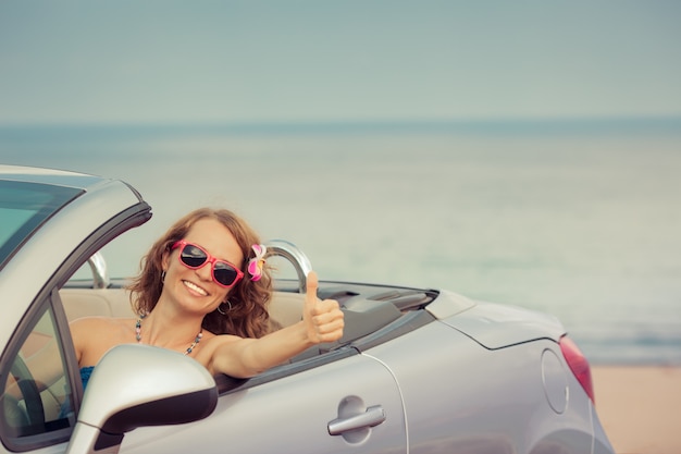 Donna felice che viaggia in macchina al mare Ragazza che si diverte in cabriolet Concetto di vacanza estiva